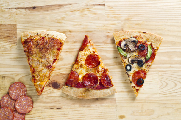 Three baked pizza pie on wooden surface - Photo, Image