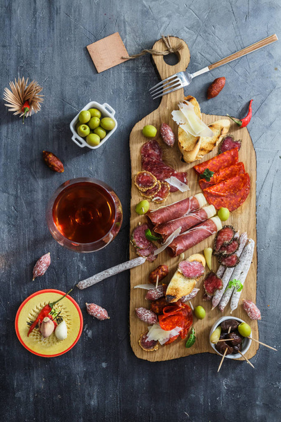 Verschillende Spaanse embutidos op een tafel: jamón, chorizo, salami, kaas en wijn. Bovenaanzicht - Foto, afbeelding