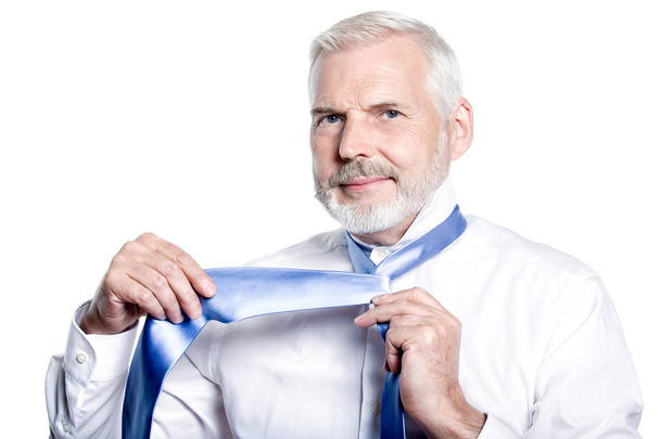 man senior getting dressed tying windsor necktie - Foto, afbeelding