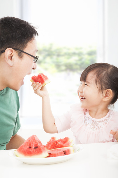 Счастливая маленькая девочка с отцом едят фрукты
 - Фото, изображение