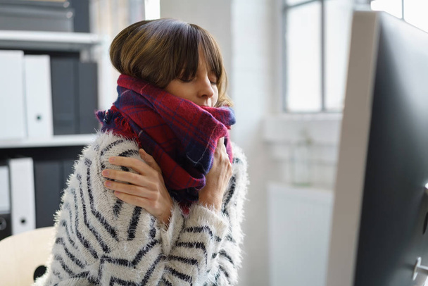 Sick businesswoman sitting shivering in the office - Photo, Image