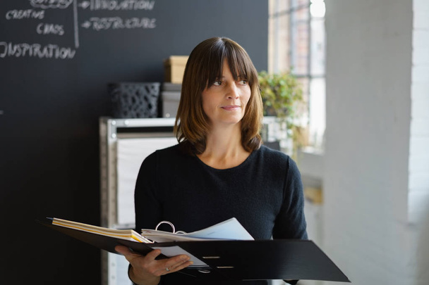 Businesswoman standing in the office with a binder - Φωτογραφία, εικόνα