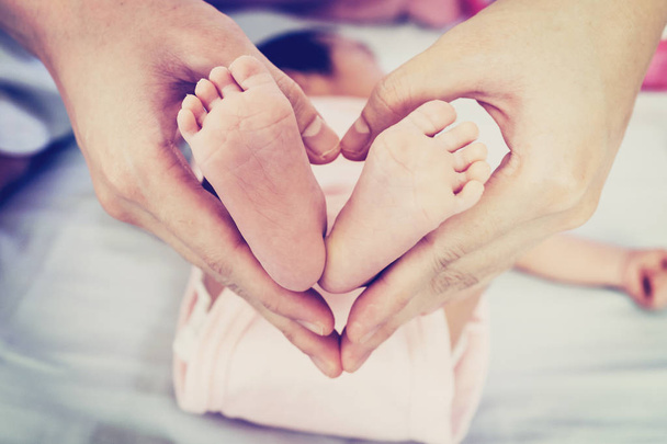 Los pies del bebé en la mano de la madre
 - Foto, imagen