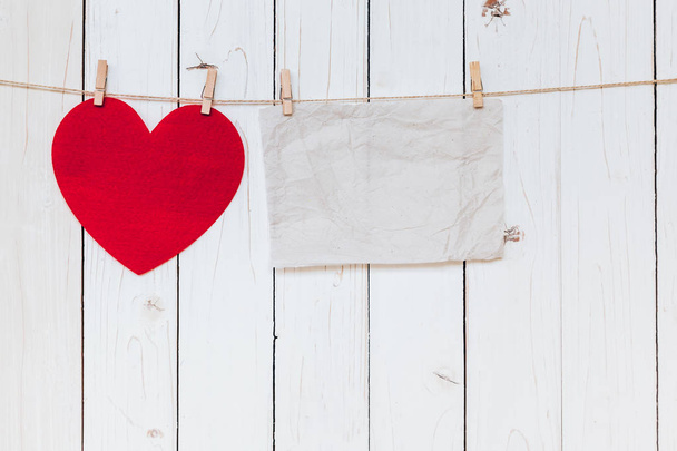 Corazón rojo y papel viejo en blanco colgando en tendedero en madera whi
 - Foto, Imagen