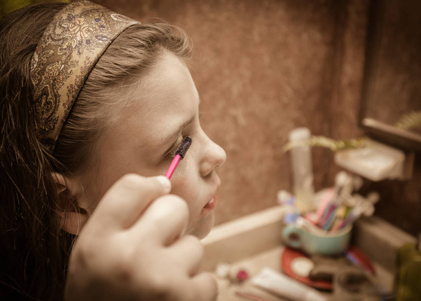 nice close seup view of little girl doing makeup on her eyes
  - Фото, изображение