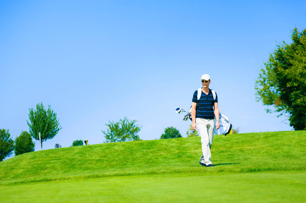 Hombre caminando a su pelota de golf
 - Foto, imagen