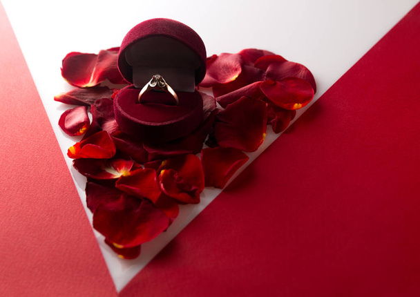 Ehering auf einem Herz aus Rosenblättern Ecke rot-weißen Hintergrund - Foto, Bild