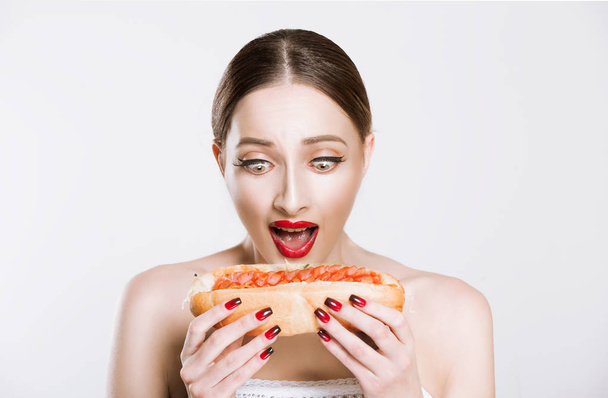 beautiful funny woman with red lips holding a burger about to bite eat isolated white grey background. Unhealthy eating life concept - Foto, afbeelding