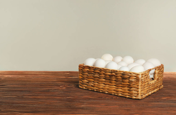 Raw eggs in wicker basket - Foto, afbeelding