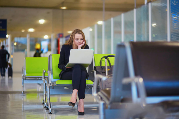 Woman in international airport terminal, working on her laptop - Fotoğraf, Görsel