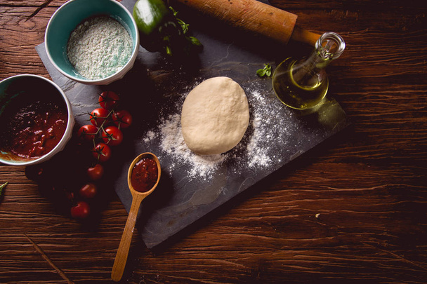 Dough with flour on wooden table, preparing homemade pizza - Photo, image