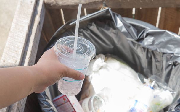 Női kéz meredek lejtő kupa dobott újrahasznosítás bin, kéz tart - Fotó, kép