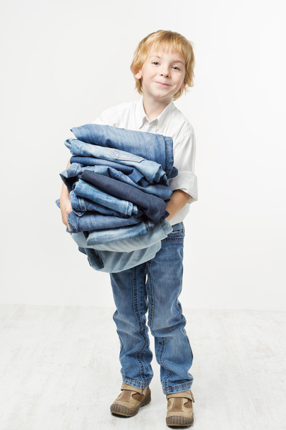 Child holding jeans stack. Kids clothing fashion. White backgrou - Foto, afbeelding