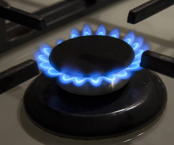 Hořící plynový sporák varná deska modré plameny zblízka ve tmě na blac - Fotografie, Obrázek