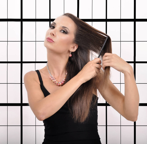 Belle jeune femme se brossant les cheveux sur un fond abstrait
 - Photo, image