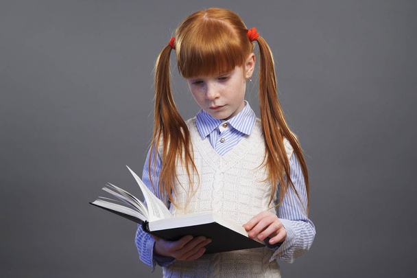 Cute redhead girl is reading a book - Φωτογραφία, εικόνα