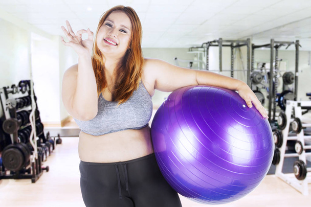 Obese female holds fitness ball - Foto, imagen