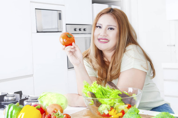 Overweight blonde woman holds tomato - 写真・画像