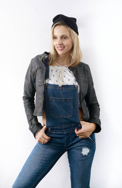 Beautiful young blonde woman with jeans overalls - Фото, изображение