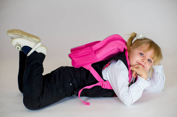 portrait of young lying schoolgirl with schoolbag - Foto, Imagen
