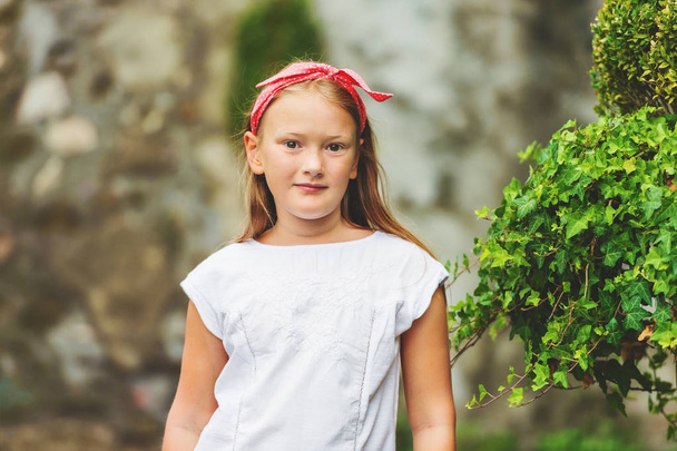 Retrato al aire libre de linda niña de 8-9 años con diadema roja
 - Foto, imagen