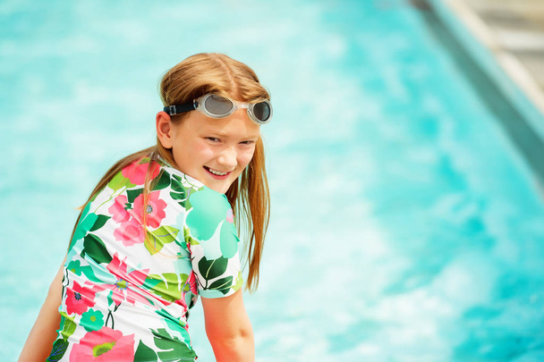 Pikkutyttö pitää hauskaa uima-altaassa mukavana kesäpäivänä.
 - Valokuva, kuva