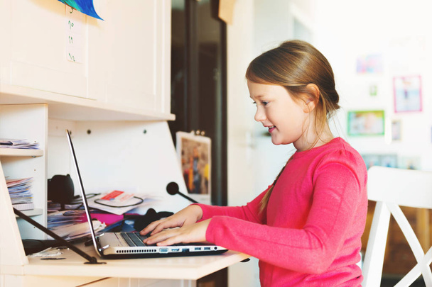 kleines Mädchen beim Hausaufgabenmachen mit Laptop - Foto, Bild