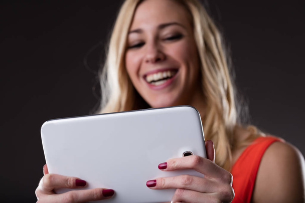tableta digital conectada inalámbrica sostenida por una mujer rubia sonriente
 - Foto, imagen