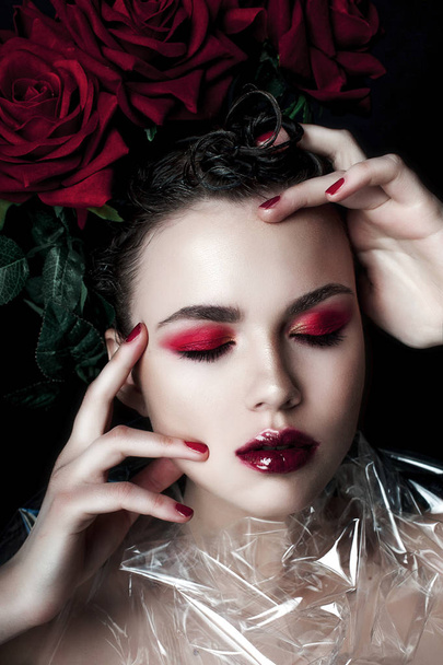 Beauty Fashion Model Woman face. Portrait with Red Rose flowers. Red Lips and Nails. Beautiful Brunette Woman with Luxury Makeup, perfect skin. Valentine. - Φωτογραφία, εικόνα