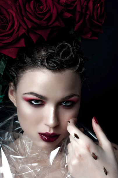 Πρόσωπο ομορφιάς γυναίκα πρότυπο μόδας. Προσωπογραφία με κόκκινο τριαντάφυλλο λουλούδια. Κόκκινα χείλη και τα νύχια. Όμορφη μελαχρινή γυναίκα με πολυτέλεια μακιγιάζ, τέλειο δέρμα. Ημέρα του Αγίου Βαλεντίνου. - Φωτογραφία, εικόνα