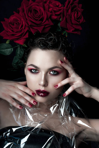Πρόσωπο ομορφιάς γυναίκα πρότυπο μόδας. Προσωπογραφία με κόκκινο τριαντάφυλλο λουλούδια. Κόκκινα χείλη και τα νύχια. Όμορφη μελαχρινή γυναίκα με πολυτέλεια μακιγιάζ, τέλειο δέρμα. Ημέρα του Αγίου Βαλεντίνου. - Φωτογραφία, εικόνα