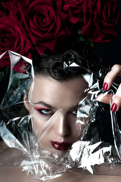 Beauty Fashion Model Woman face. Portrait with Red Rose flowers. Red Lips and Nails. Beautiful Brunette Woman with Luxury Makeup, perfect skin. Valentine. - Fotografie, Obrázek