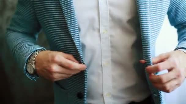 Ręce człowieka, zapinane na guziki strój casual kurtka z bliska. Stylowe, dobrze ubrany mężczyzna próbuje na niebieski prążkowany garnitur przygotowuje się do wyjścia. Macho luksusowych dopasować rozmiar odzieży złotej młodzieży styl zakład koncepcja - Materiał filmowy, wideo