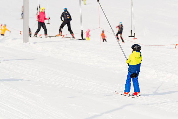 Ребенок на лыжном подъемнике поднимается в гору
 - Фото, изображение