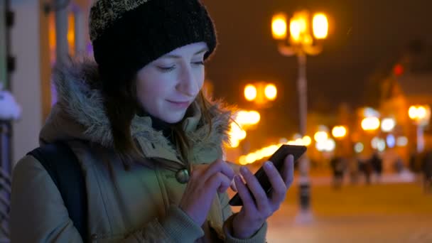 Mladá krásná žena pomocí smartphone ve městě v noci - Záběry, video