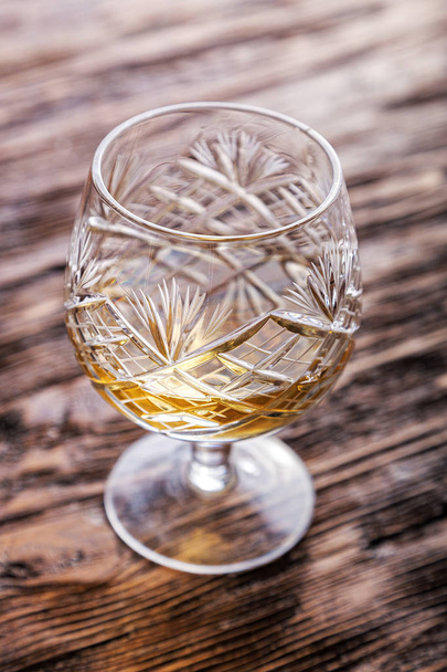a glass of brandy on a wooden background - Foto, afbeelding