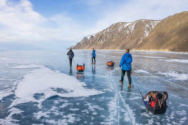 woman and a man with a sledge and trekking pole is ice of Baikal - Fotoğraf, Görsel