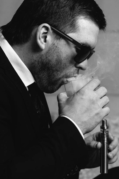 man with a glass of whiskey and electronic cigarette - Foto, imagen