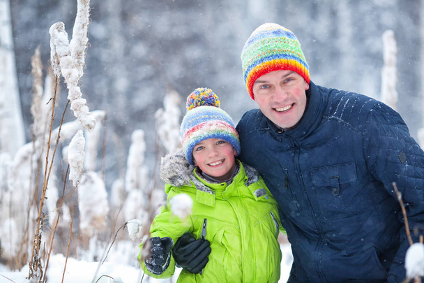 Портрет счастливой семьи в зимнем парке. Отец, сын и маленькая дочь смеются
 - Фото, изображение