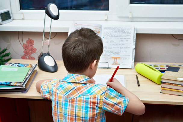 Boy does his homework at  table - Фото, изображение