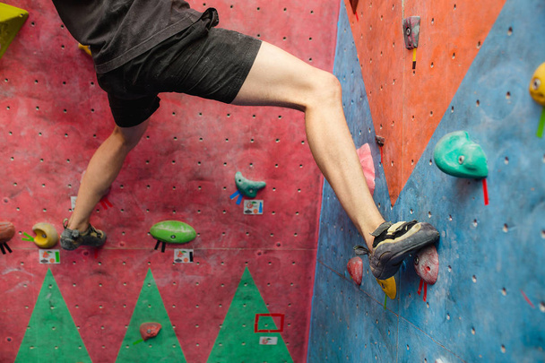 Man climbing artificial boulders in gym, close-up view of legs with special shoes - Photo, Image