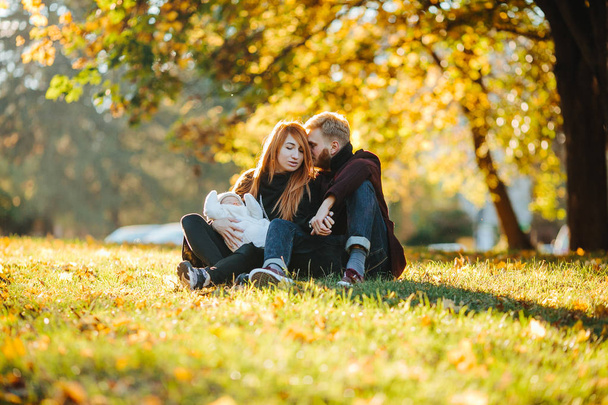 young family and newborn son in autumn park - Photo, Image