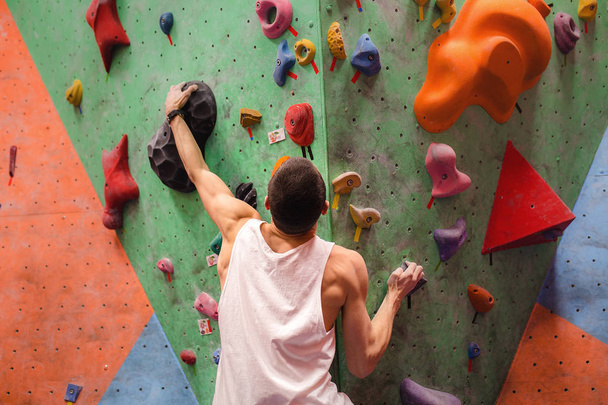Man climber on artificial climbing wall in bouldering gym - Photo, Image