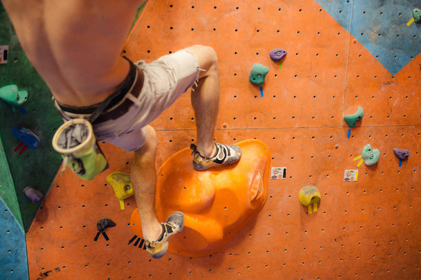 Homme escalade rochers artificiels dans la salle de gym, vue rapprochée des jambes avec des chaussures spéciales
 - Photo, image