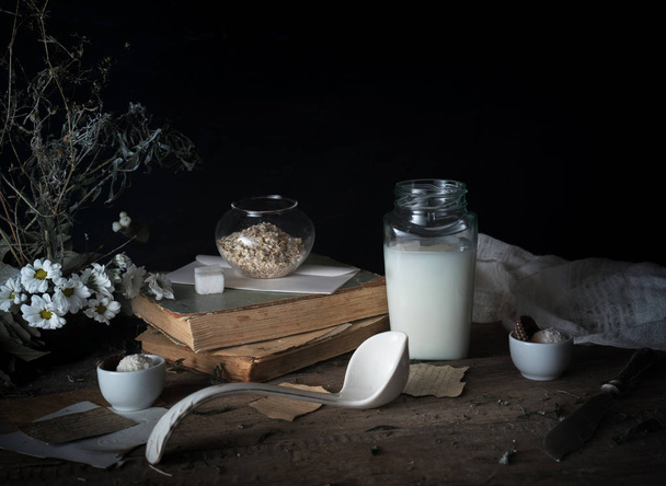 rustic breakfast. still life, vintage. the book chrysanthemums, the milk bank. black background - Zdjęcie, obraz