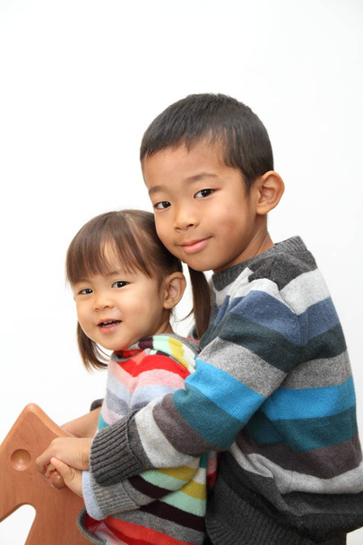 Ιαπωνικά αδελφός και αδελφή παίζοντας με Αλογάκι (7 ετών αγόρι και 2 χρόνια παλιά κορίτσι) - Φωτογραφία, εικόνα