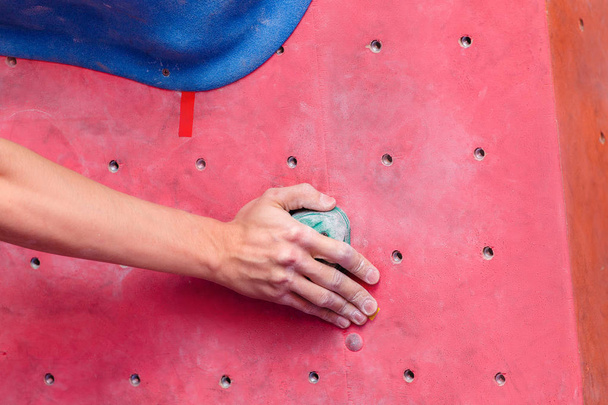 Closeup of man's hand on handhold on artificial climbing wall, thumbs with magnesia - Foto, imagen