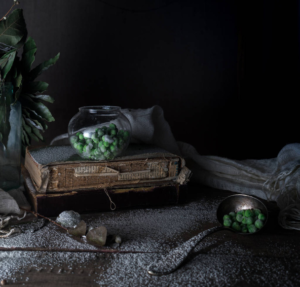 rustieke stilleven, vintage. groene erwten, oude boeken, meel op een houten tafel. donkere achtergrond - Foto, afbeelding