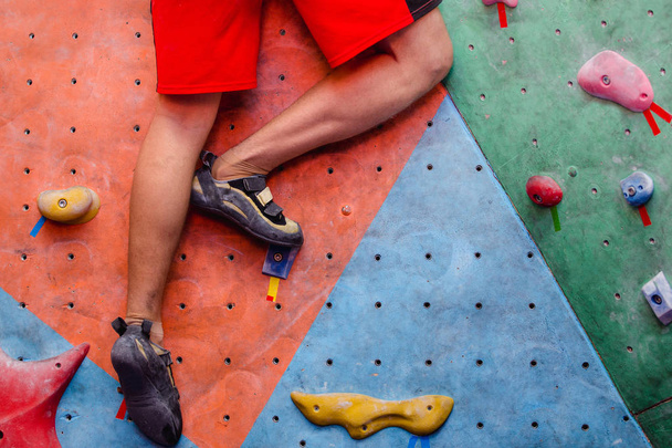 Hombre escalando rocas artificiales en el gimnasio, vista de cerca de las piernas con zapatos especiales
 - Foto, Imagen