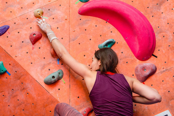 Young woman practicing in bouldering on a rock wall indoors - Photo, Image